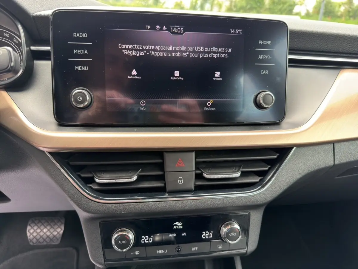 Vue plongeante sur la roue de secours galette noire et son kit d'outils dans le coffre du Skoda Kamiq gris clair.