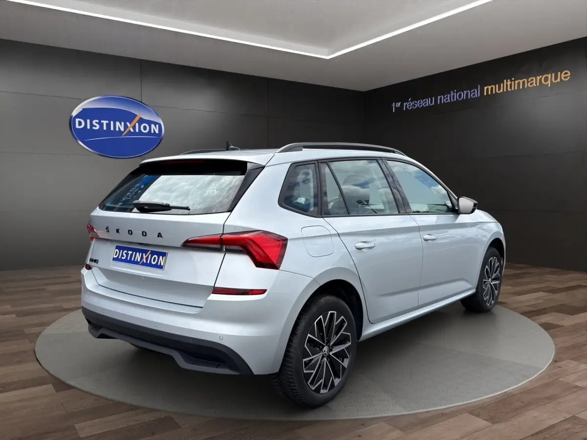 Vue arrière d'un Skoda Kamiq gris clair 2023 avec feux LED et logo distinctif sur fond showroom.
