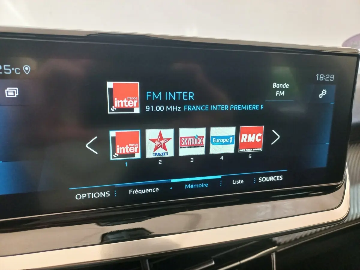 Écran tactile central de la Peugeot 208 PureTech 100 noir, affichant les stations radio FM en intérieur.