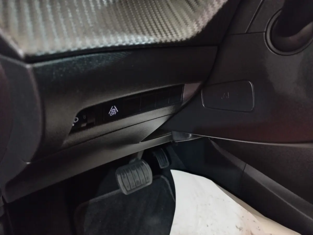 Détail intérieur côté gauche montrant les commandes sous le tableau de bord et la pédale de frein d'une Peugeot 208 noire.