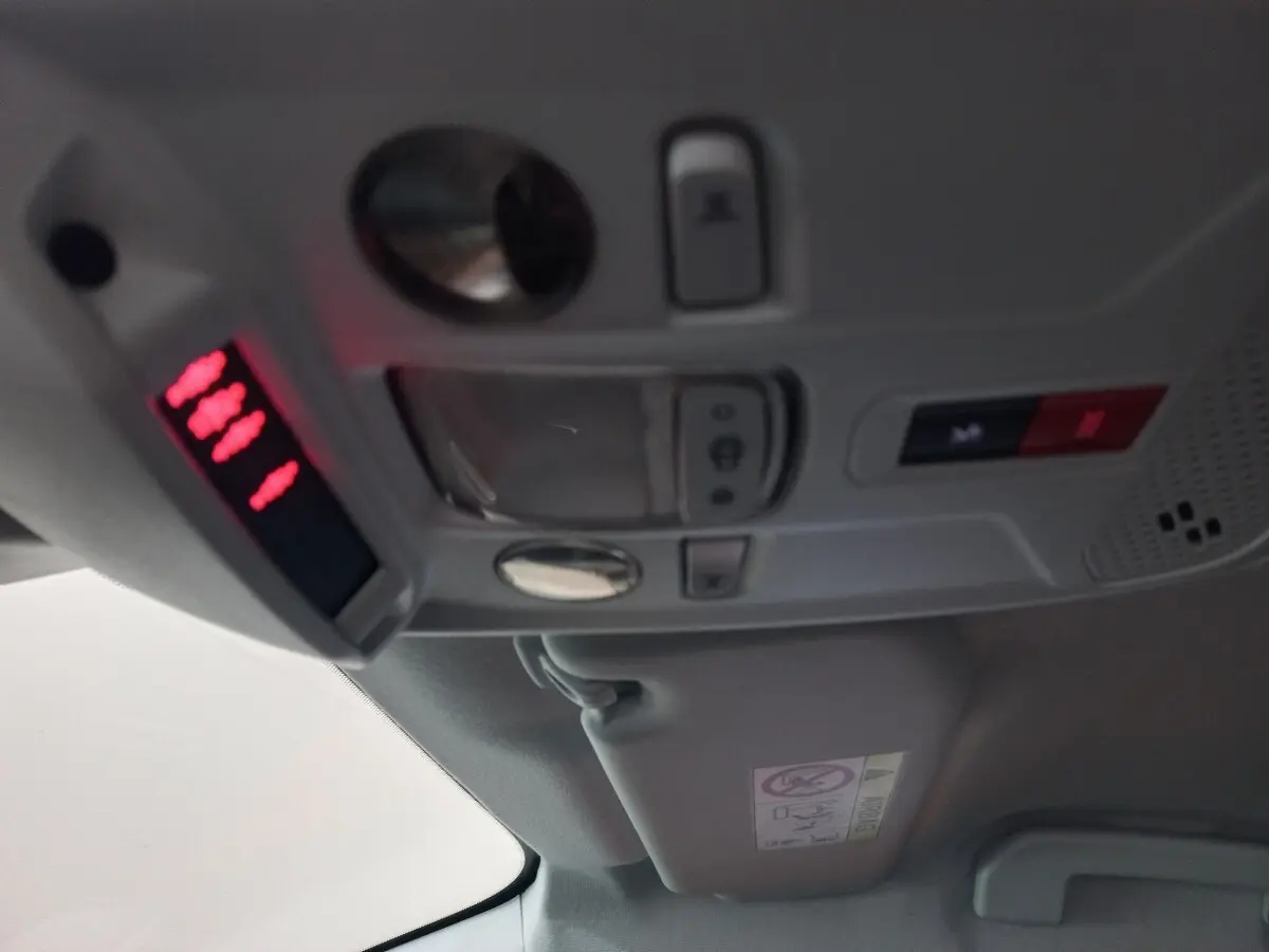 Vue intérieure du plafond avec commandes d'éclairage et panneau d'alerte rouge dans une Peugeot 208 noire 2022.