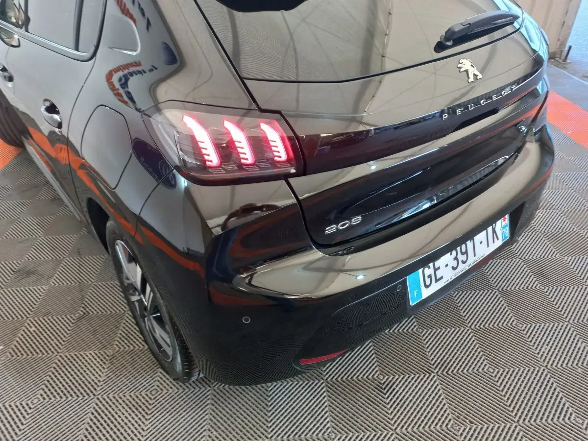 Vue 3/4 arrière gauche d'une Peugeot 208 noire de 2022 avec feux arrière LED caractéristiques allumés.