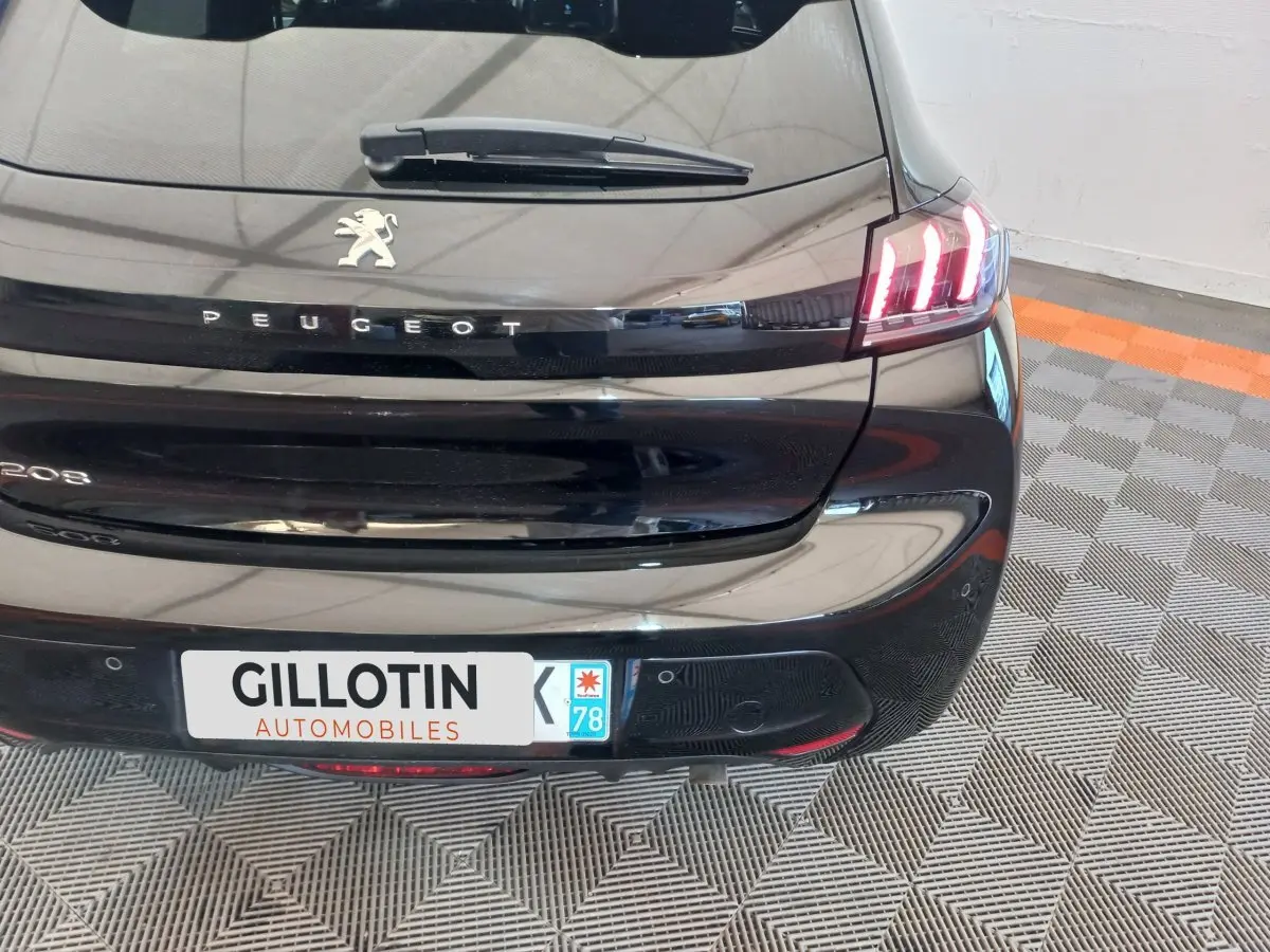 Vue arrière droite d'une Peugeot 208 noire 2022 avec feux LED distinctifs et logo Peugeot visible.