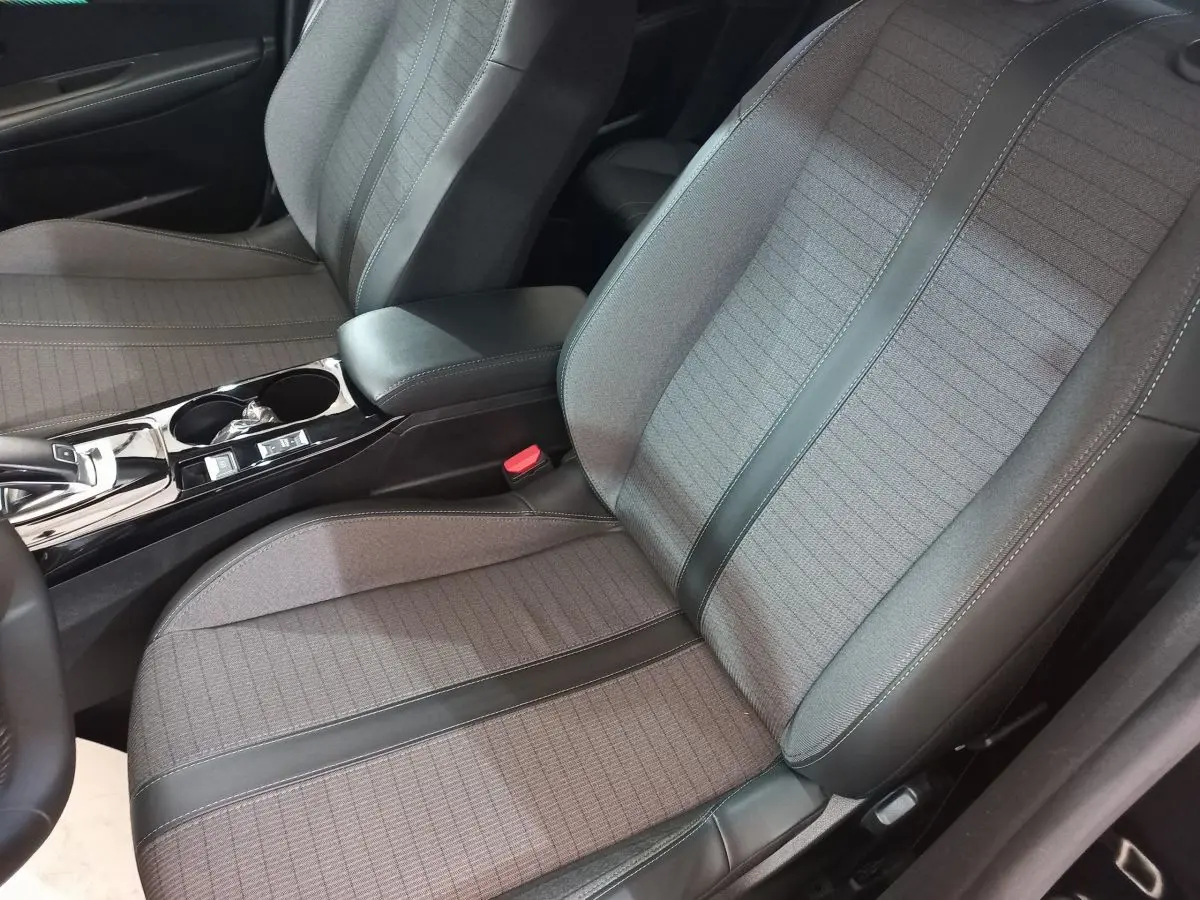 Gros plan sur les sièges avant gris et noirs de la Peugeot 208 PureTech 100 Allure Pack, avec console centrale visible.