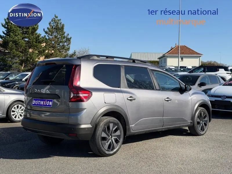 Vue 3/4 arrière droite du Dacia Jogger gris schiste métallisé 2025, break familial 7 places avec toit noir et jantes distinctives.