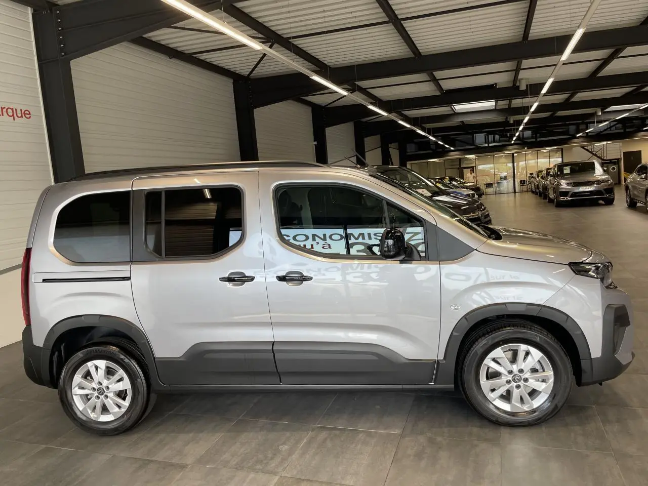 Peugeot Rifter gris Artense vue de profil côté gauche, portes coulissantes et jantes tôles 16 pouces visibles.