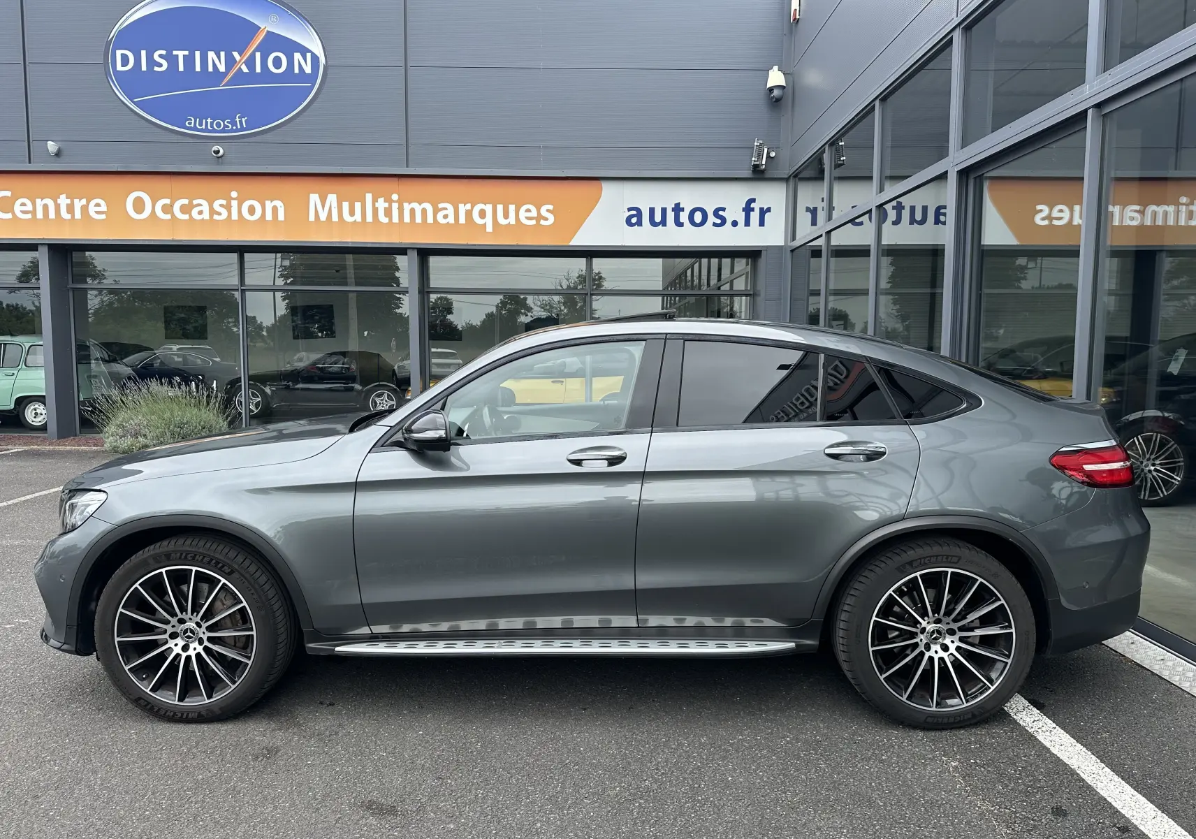Vue de profil côté gauche d'un Mercedes GLC Coupé 250 D Fascination gris foncé avec jantes alliage et marchepieds.