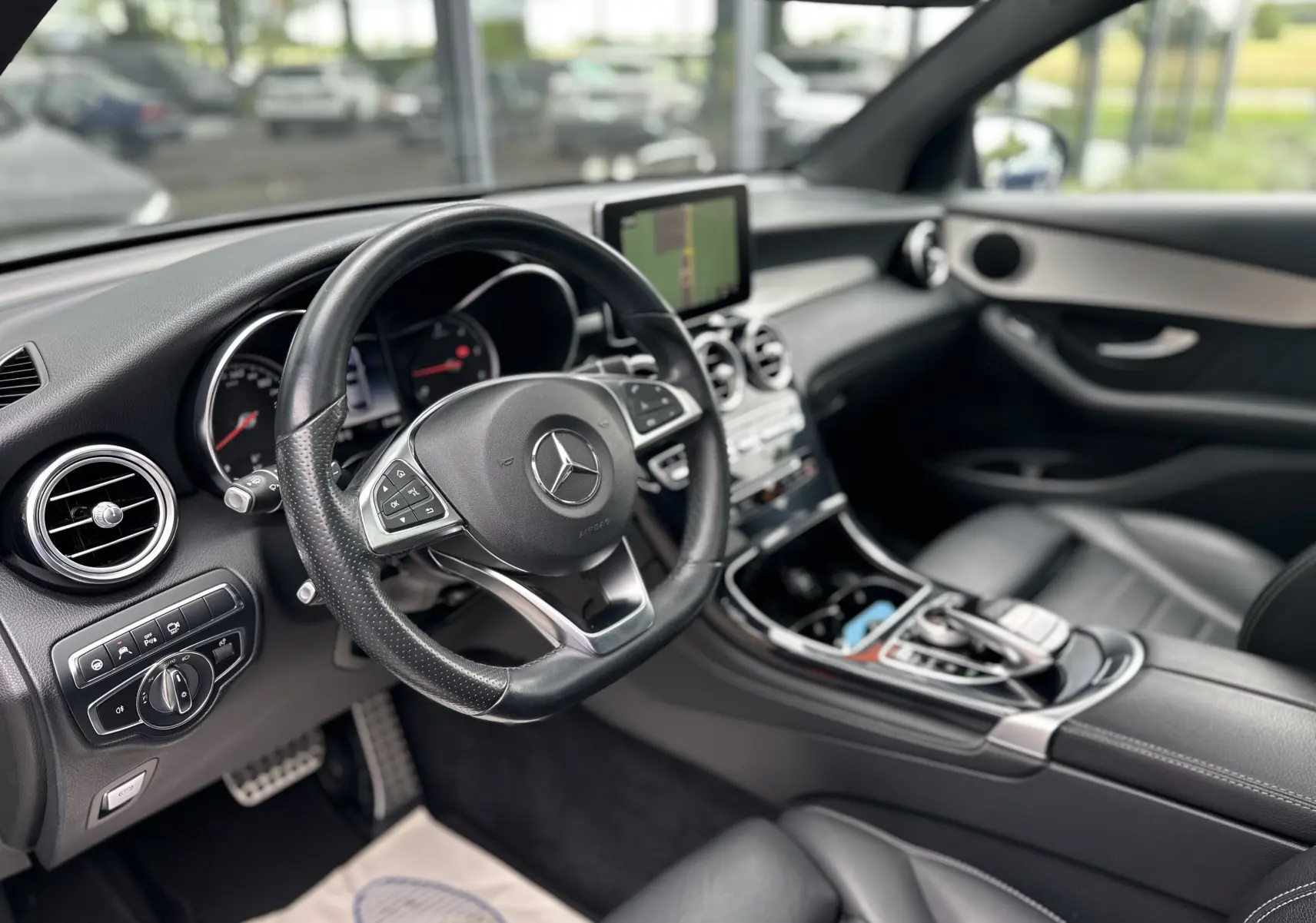Vue intérieure côté conducteur du Mercedes GLC Coupé 250 D Fascination 2018 avec tableau de bord noir et écran central.
