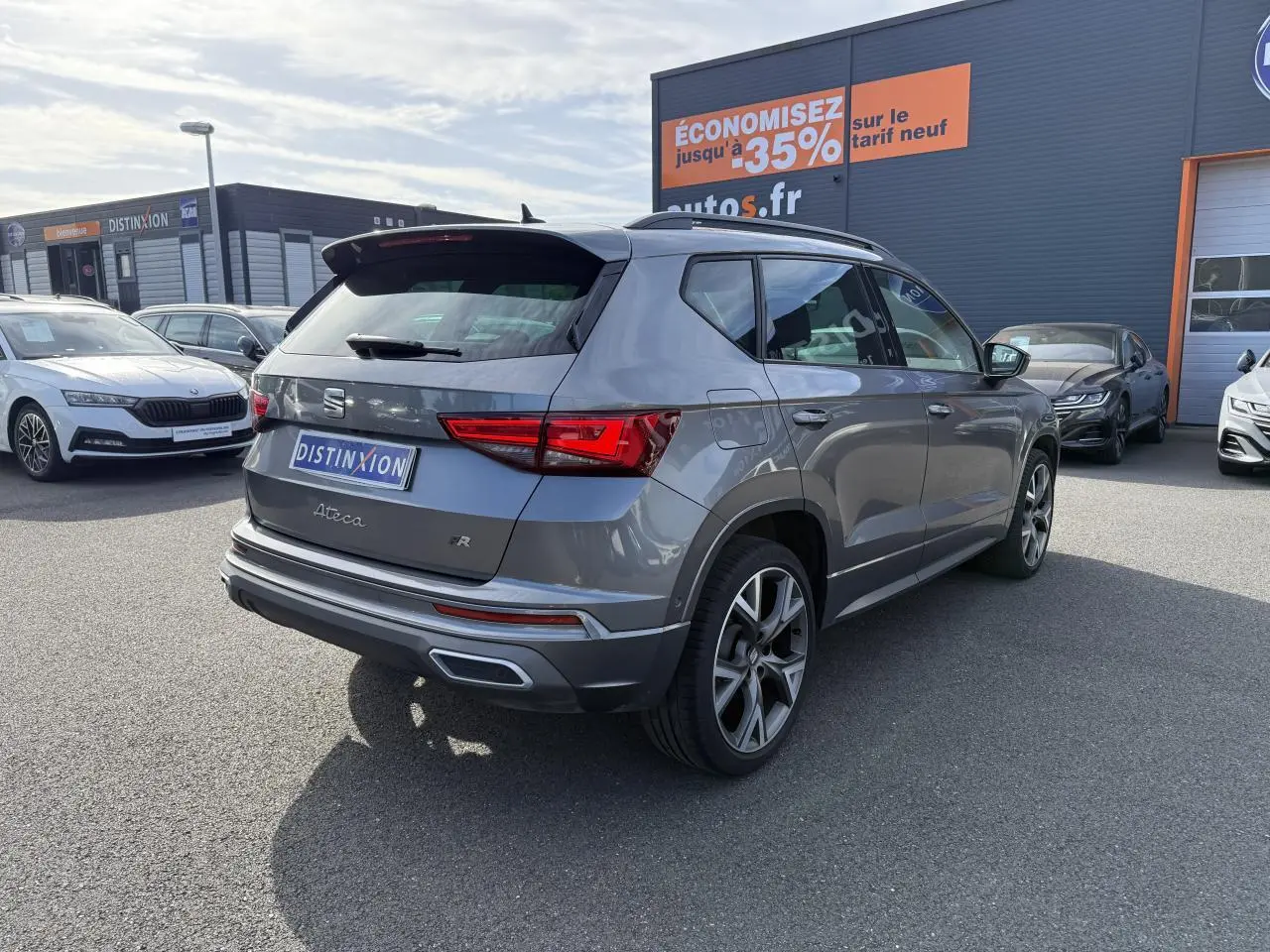 Vue 3/4 arrière droite d'un SEAT Ateca FR gris graphite avec jantes alu 19 pouces et feux LED arrière allumés.