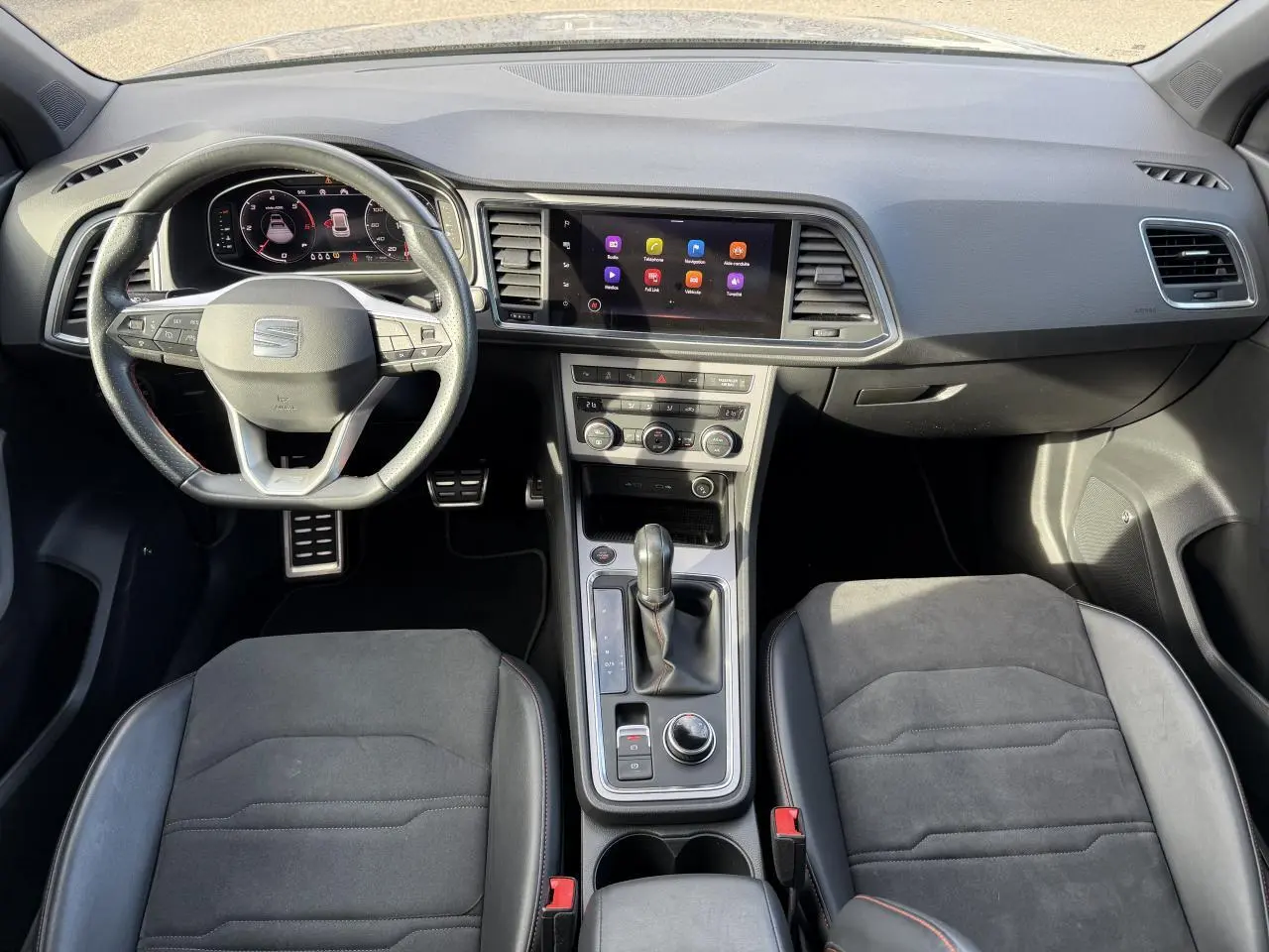 Vue intérieure frontale du tableau de bord et console centrale du SEAT Ateca gris graphite avec volant sport multifonction et écran tactile.