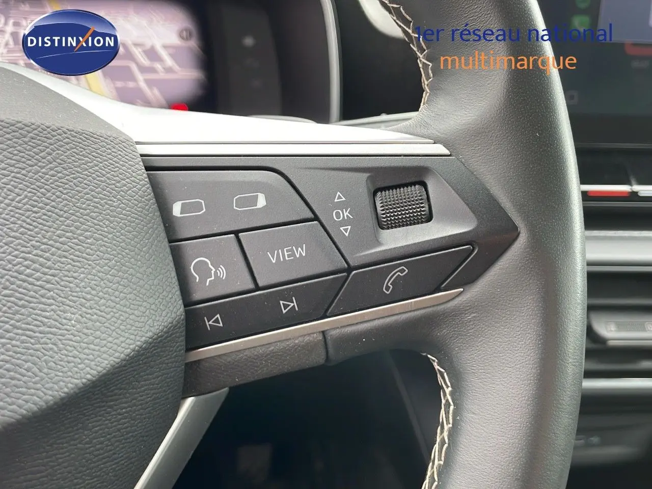 Gros plan sur les commandes multifonctions du volant en cuir noir du SEAT LEON ST gris urbain 2023.