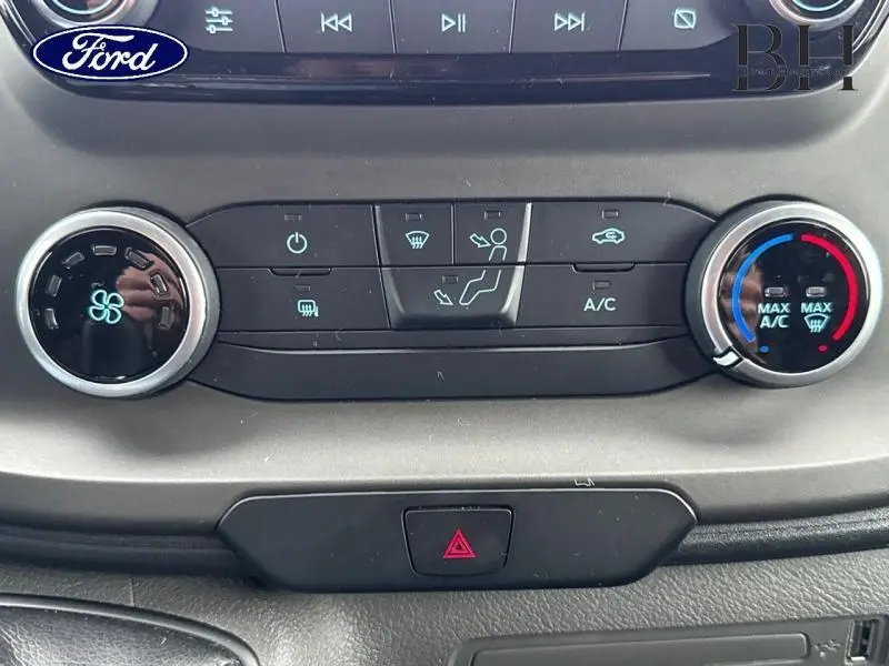 Gros plan sur les commandes de climatisation du Ford Transit Custom noir, avec réglages de ventilation et température visibles.