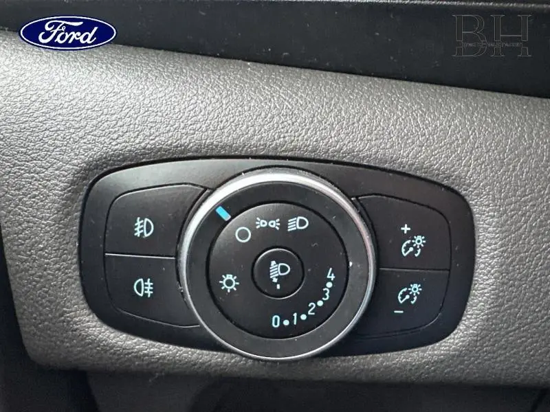 Gros plan sur le panneau de commande des phares du Ford Transit Custom noir, avec réglages d'éclairage et antibrouillard.