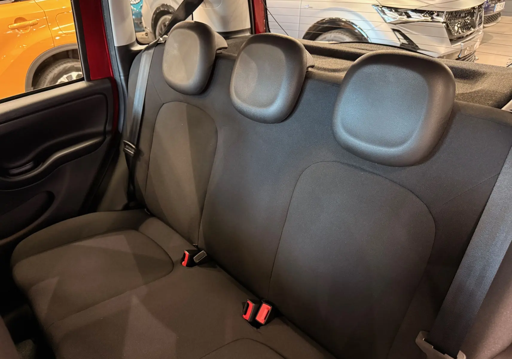 Vue intérieure sur la banquette arrière noire en tissu de la Fiat Panda 1.0 Hybrid Rouge Amore, avec appuie-têtes et ceintures visibles.