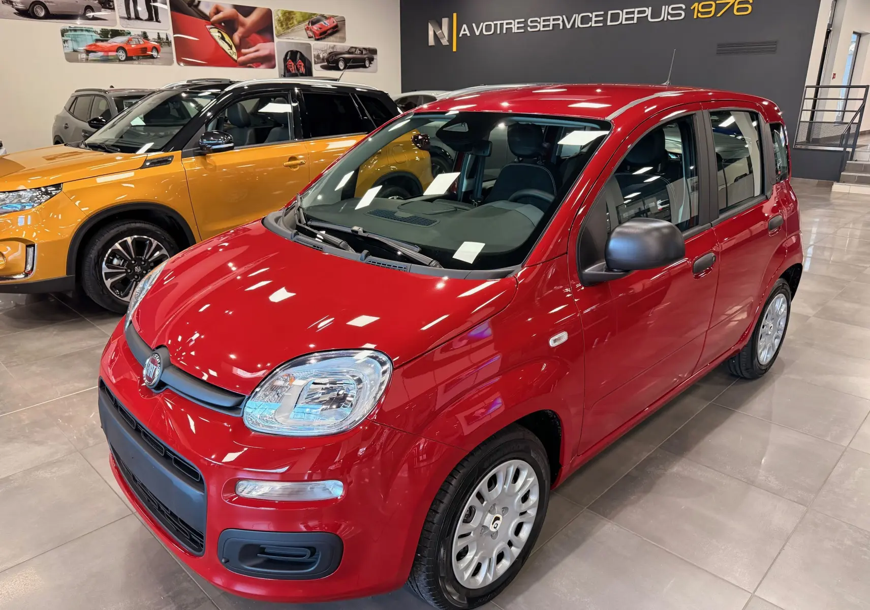 Vue 3/4 avant droite de la FIAT Panda 1.0 70 CH Hybrid City rouge Amore avec rétroviseurs noirs en concession.