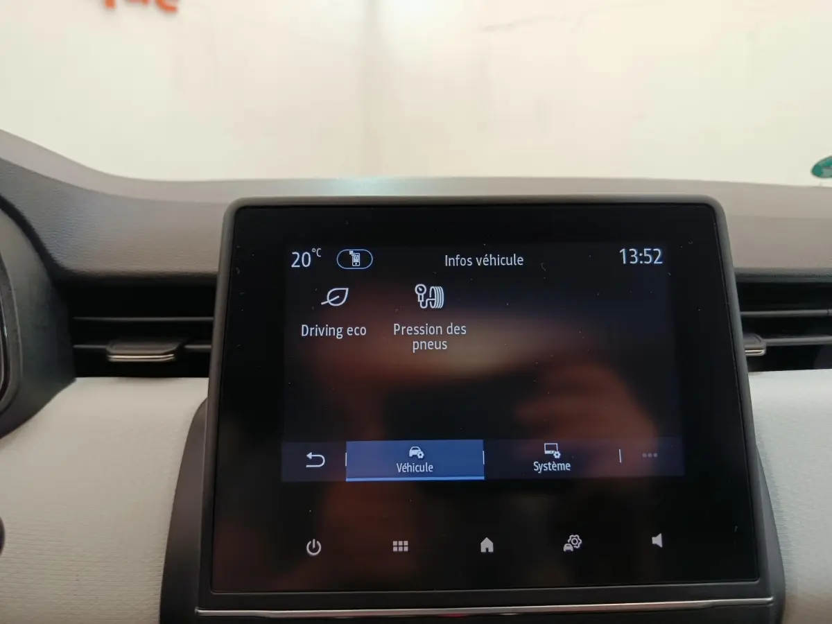Écran tactile central de la Renault Clio blanc, affichant les infos véhicule en intérieur, vue frontale rapprochée.