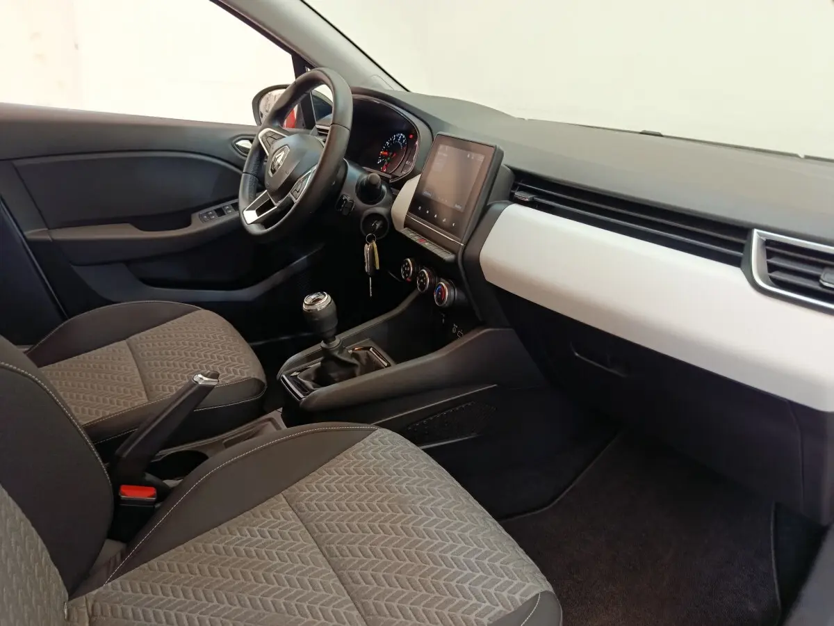Vue intérieure côté conducteur de la Renault Clio Evolution TCe 100 GPL 2023, montrant tableau de bord et sièges gris.