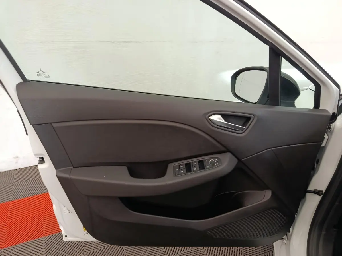 Vue intérieure de la porte avant gauche blanche d'une Renault Clio 2023, avec commandes électriques et poignée argentée.