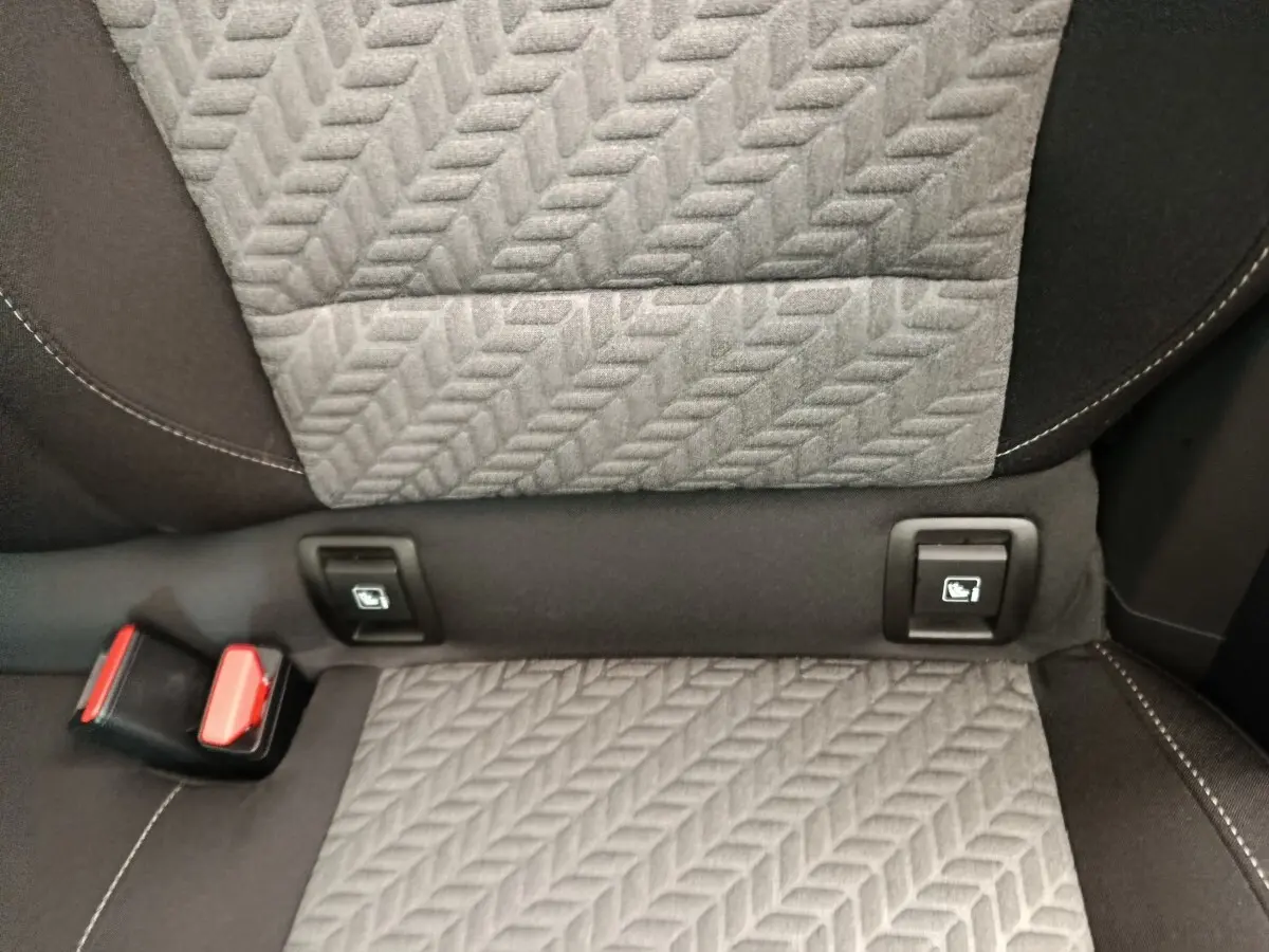Détail de la banquette arrière grise avec fixation Isofix et boucle de ceinture rouge dans une Renault Clio blanche.