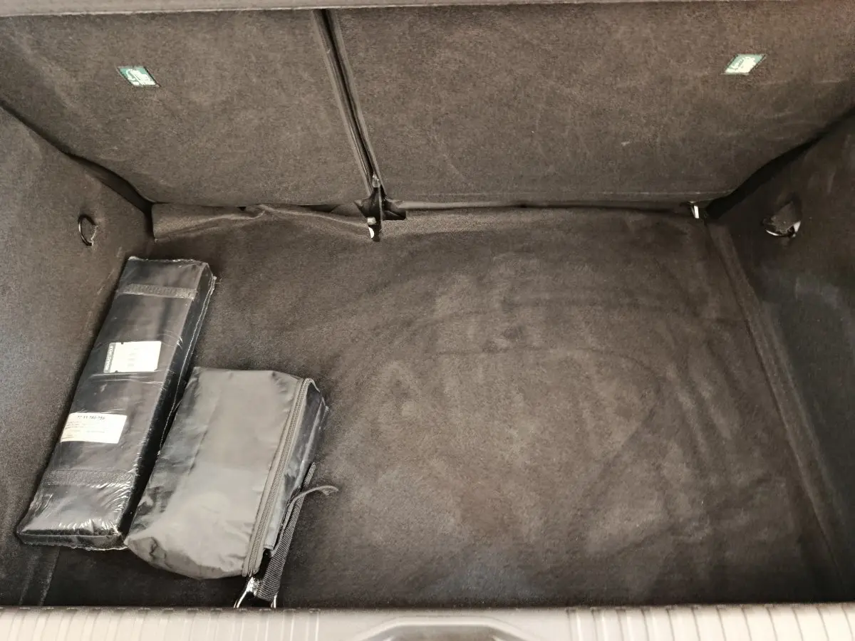 Coffre vide de Renault Clio blanc, vue intérieure montrant la moquette noire et deux sacs de rangement.