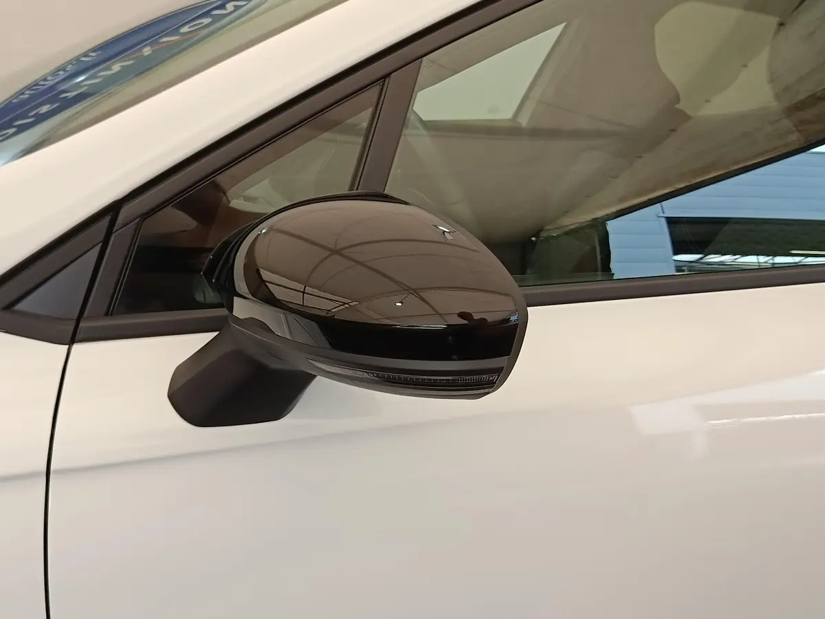 Gros plan sur le rétroviseur noir brillant côté conducteur d'une Renault Clio blanche Evolution TCe 100 GPL 2023.