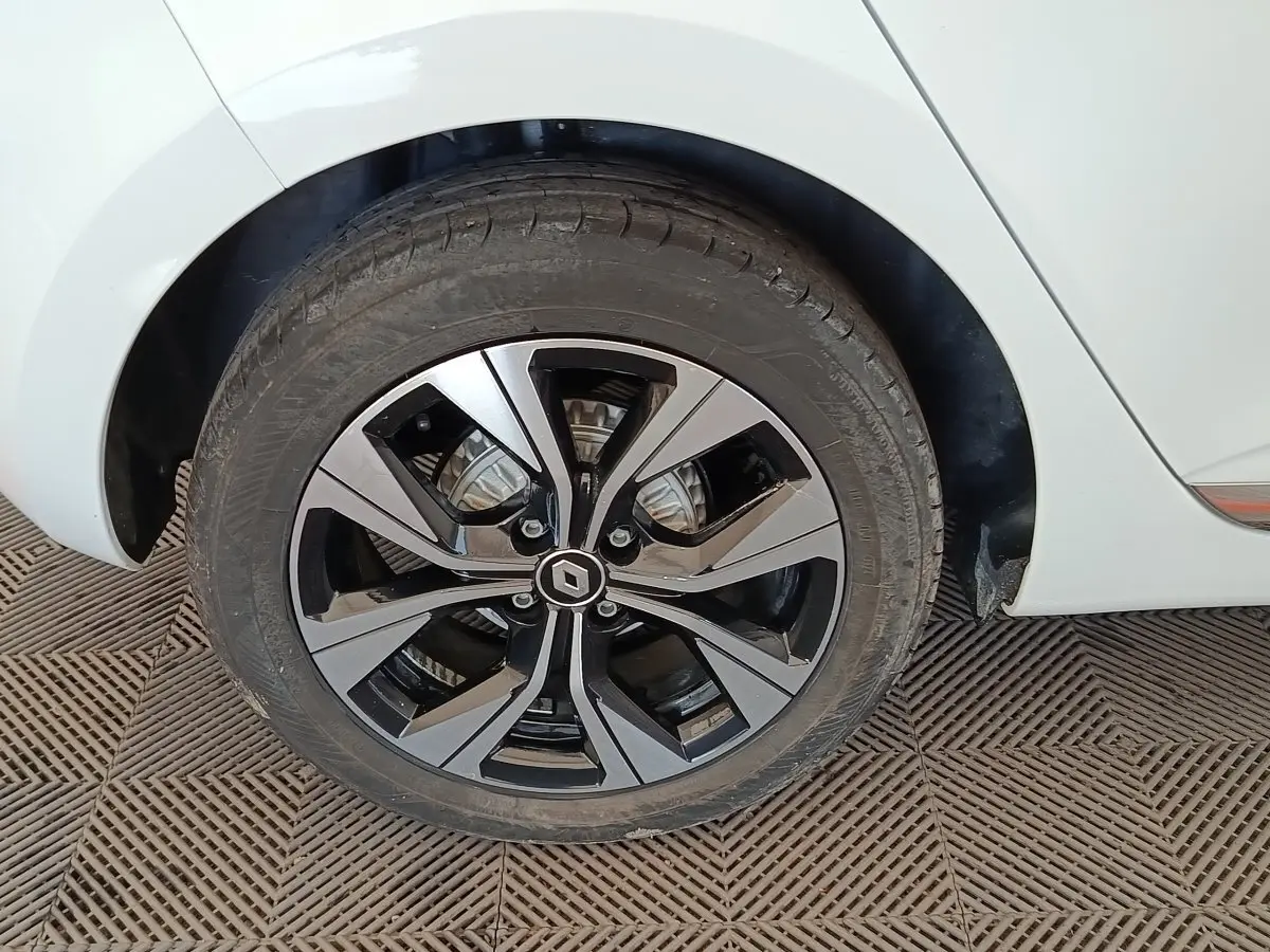 Gros plan sur la roue arrière droite de la Renault Clio blanche, avec jante alliage bicolore au design moderne.