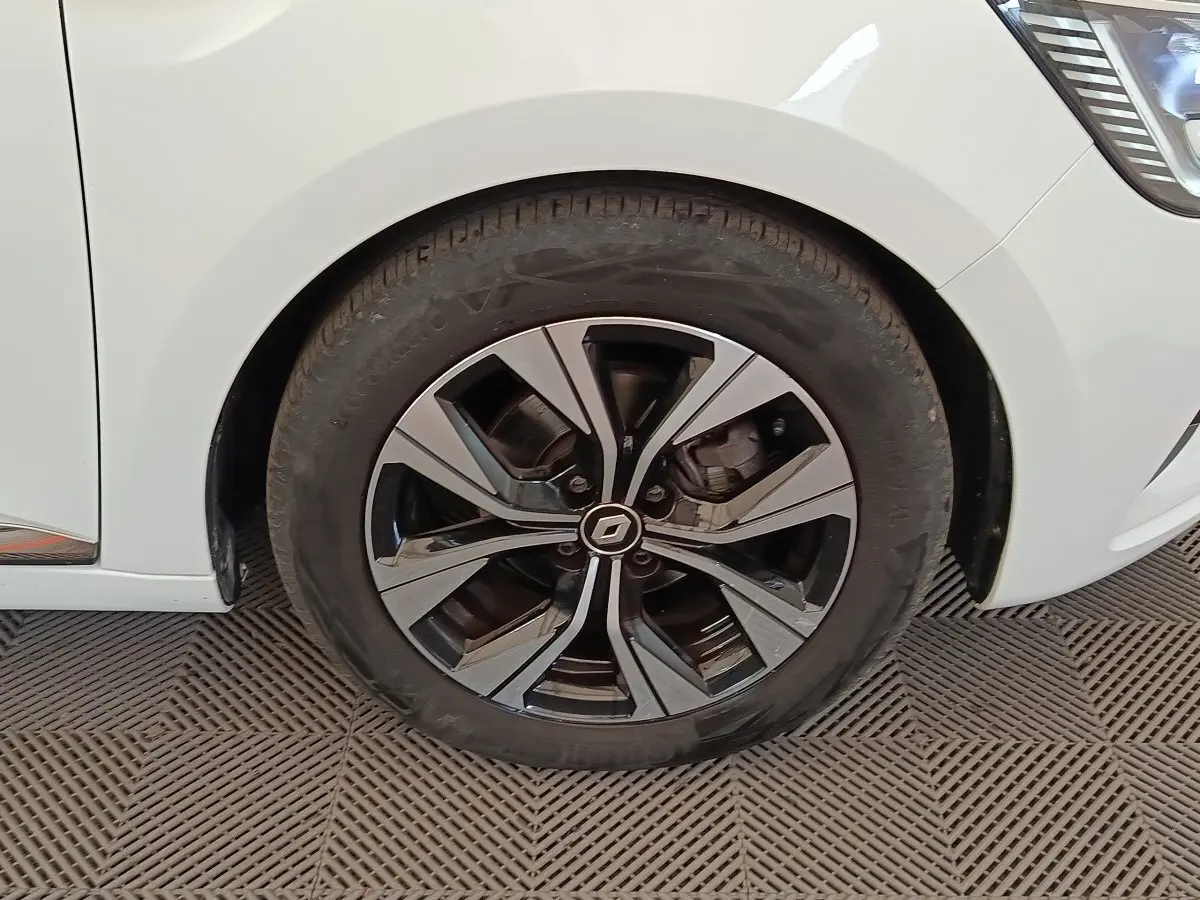 Gros plan sur la roue avant droite de la Renault Clio blanche Evolution TCe 100 GPL avec jante alliage noire et argent.