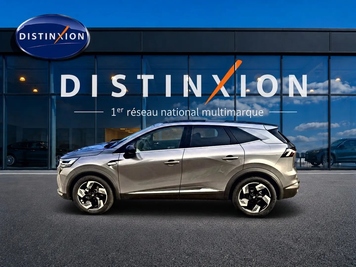 Profil droit d’un Renault Symbioz gris cassiopée avec jantes alu, stationné devant une vitrine Distinxion.