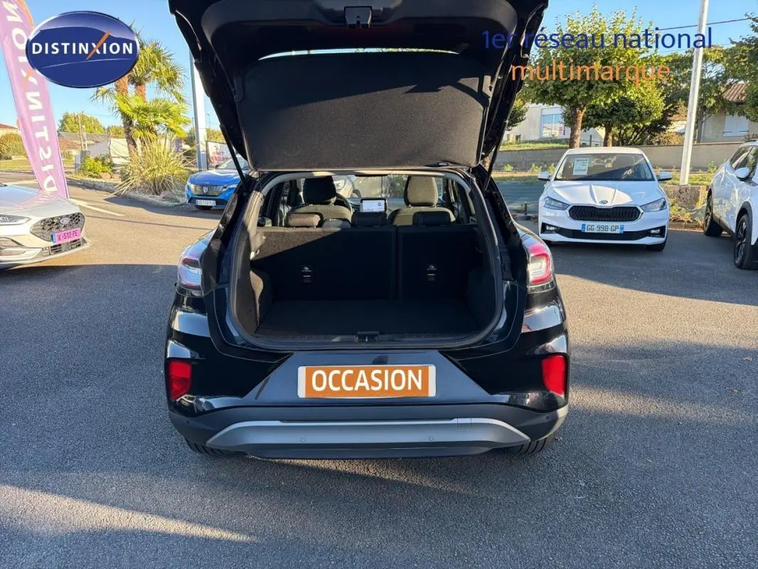 Vue arrière d’un Ford Puma noir 2023 avec coffre ouvert sur un parking en plein jour.