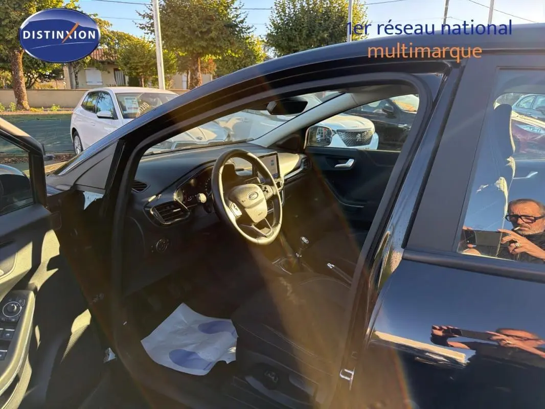 Vue intérieure côté conducteur d'un Ford Puma noir 2023 avec volant, écran tactile et sièges sport visibles.