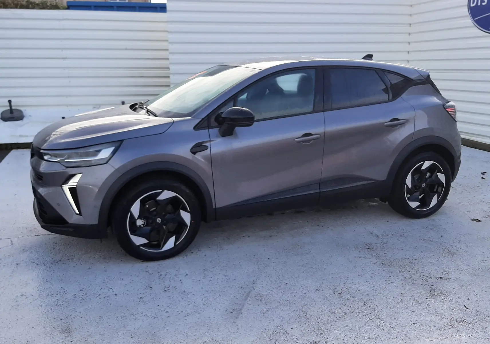 Renault Captur gris Cassiopée en vue de profil côté gauche, avec jantes noires et détails modernes LED.