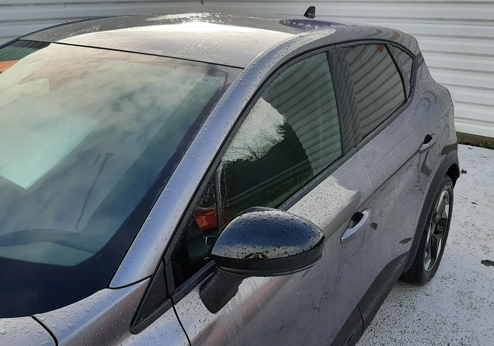 Vue 3/4 avant droit du Renault Captur gris Cassiopée avec rétroviseur noir et jantes alliage bicolores.