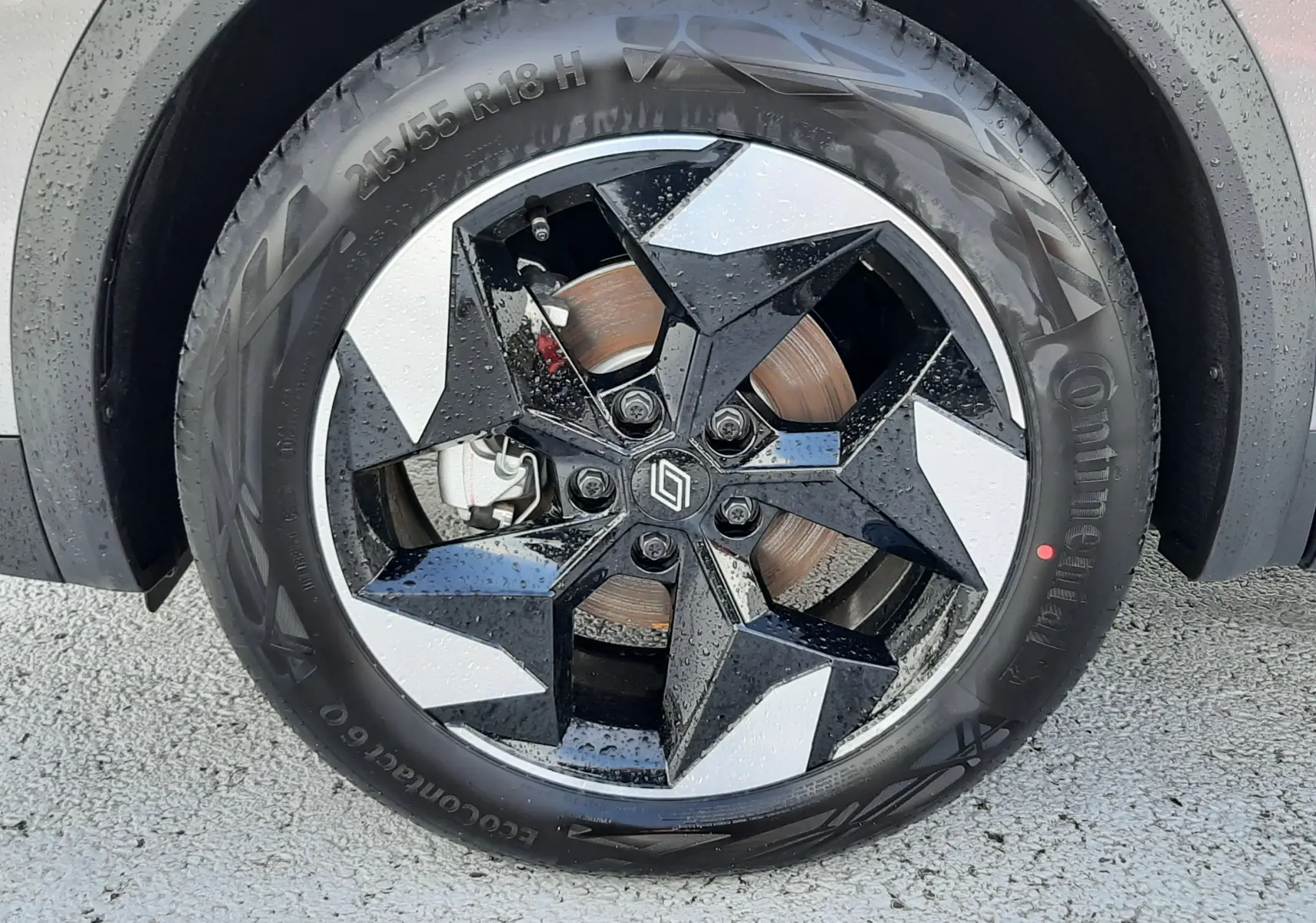 Gros plan sur la roue avant droite du Renault Captur gris Cassiopée, mettant en valeur la jante noire et argentée au design géométrique.