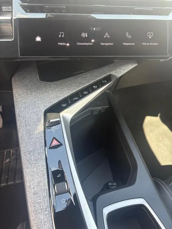 Vue rapprochée de la console centrale intérieure du Peugeot 3008 Hybrid 136 e-DCS6 Allure 2025, avec tissu gris clair et commandes tactiles.