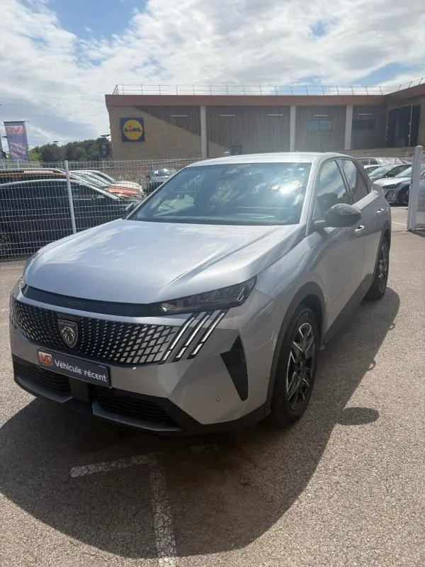 Peugeot 3008 Hybrid gris clair vue 3/4 avant droit, avec calandre distinctive et feux LED verticaux.