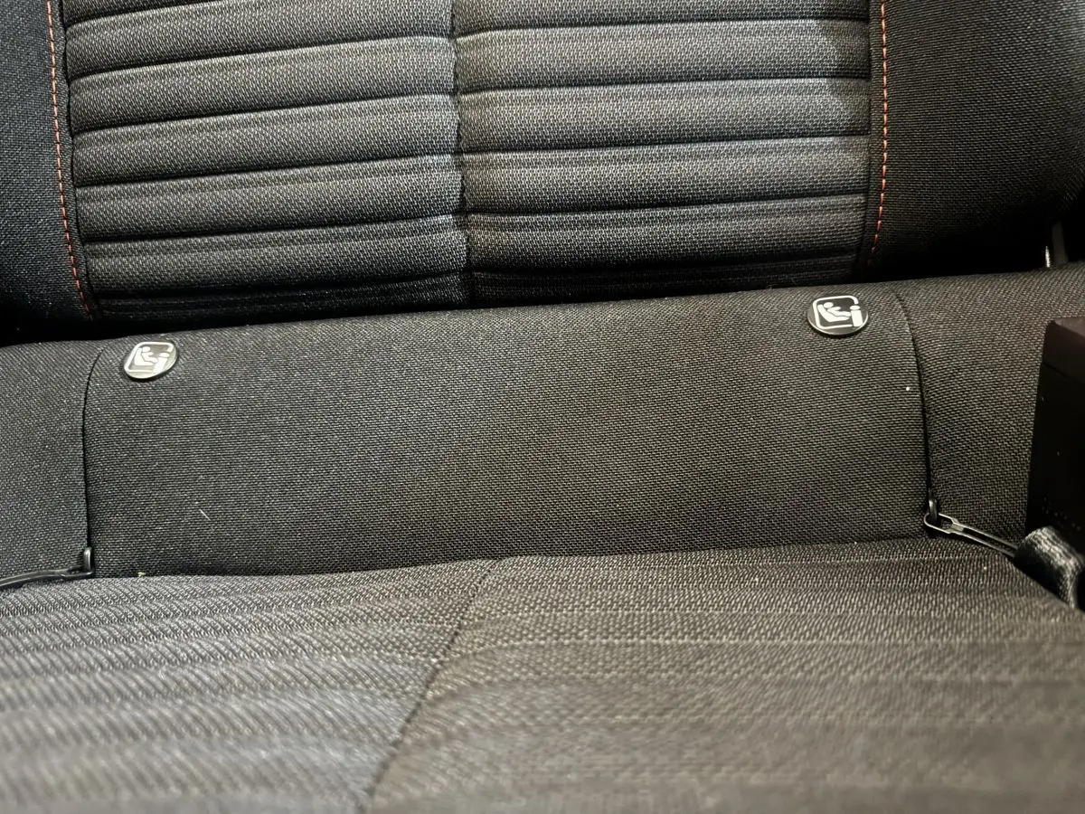 Gros plan sur la banquette arrière noire de la Peugeot 208, montrant les fixations Isofix pour siège enfant.