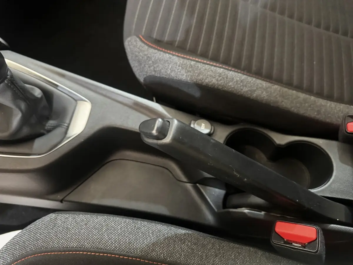 Vue rapprochée de la console centrale de la Peugeot 208 2023, montrant le frein à main manuel et porte-gobelets noirs.