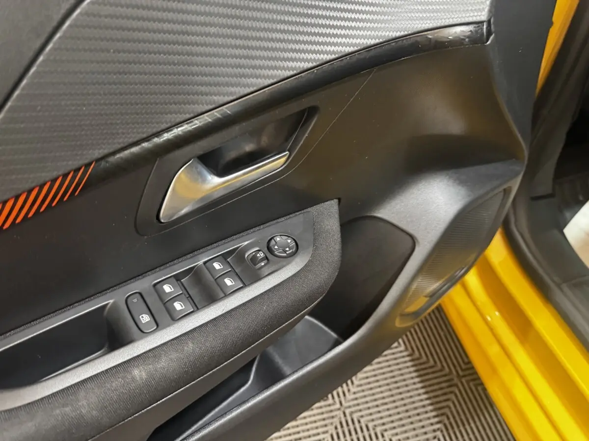 Vue rapprochée de la porte avant gauche jaune de la Peugeot 208 avec commandes des vitres et rétroviseurs.