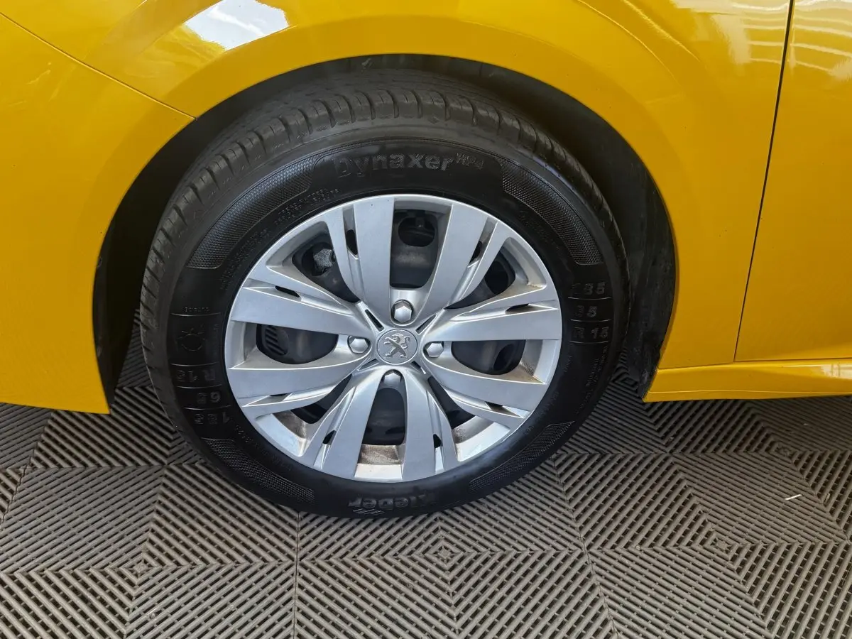 Gros plan sur la roue avant droite d'une Peugeot 208 jaune 2023 avec jante argentée et pneu Dynaxer.