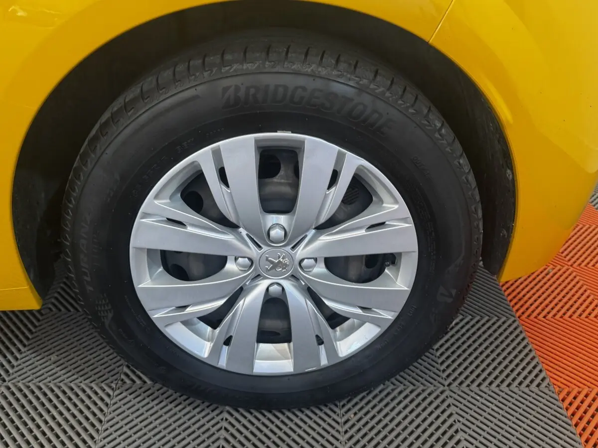 Gros plan sur la roue avant gauche d’une Peugeot 208 jaune 2023 avec jante argentée et pneu Bridgestone.