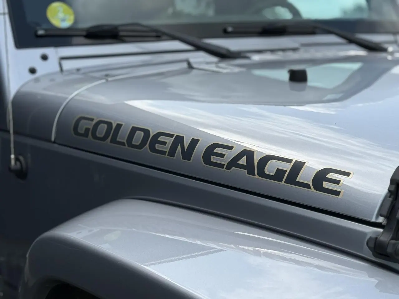 Gros plan sur le capot côté gauche d'un Jeep Wrangler Golden Eagle 2019 couleur Billet Silver avec lettrage doré.