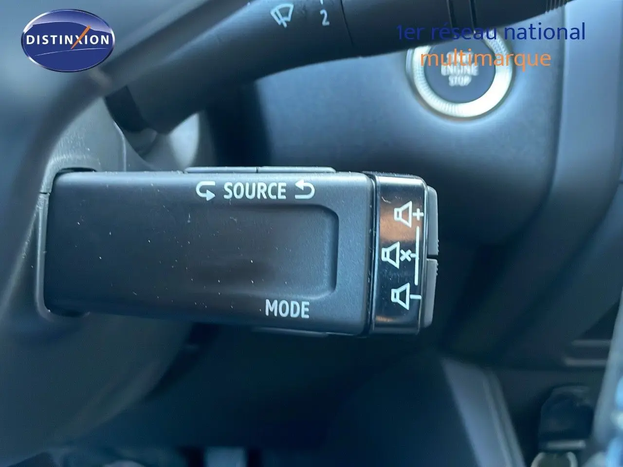 Gros plan sur la commande au volant du Renault Captur E-Tech blanc nacré, avec bouton source et mode visibles.