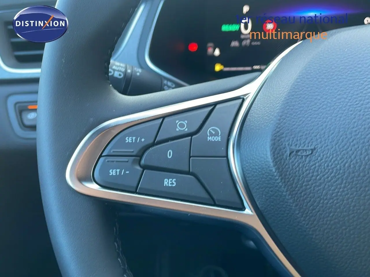 Gros plan sur les commandes à gauche du volant du Renault Captur blanc nacré 2025 avec tableau de bord numérique en arrière-plan.