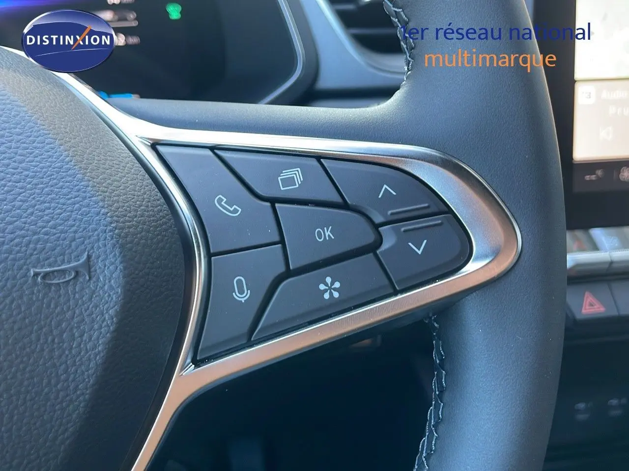 Gros plan sur les commandes au volant en cuir noir du Renault Captur E-Tech blanc nacré, mettant en valeur les boutons multifonctions.