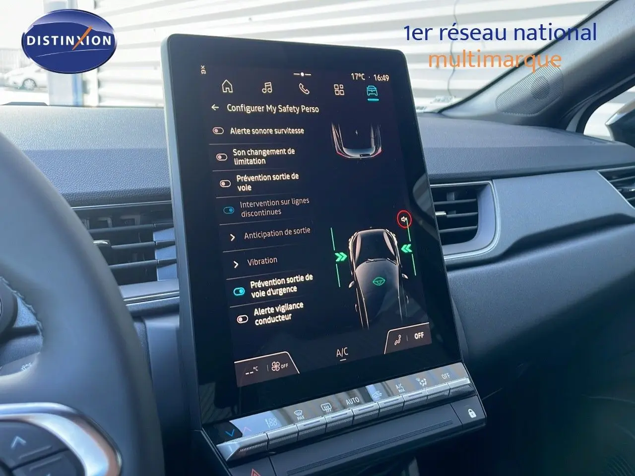 Vue rapprochée de l'écran tactile central du tableau de bord du Renault Captur blanc nacré avec toit noir, affichant les aides à la conduite.