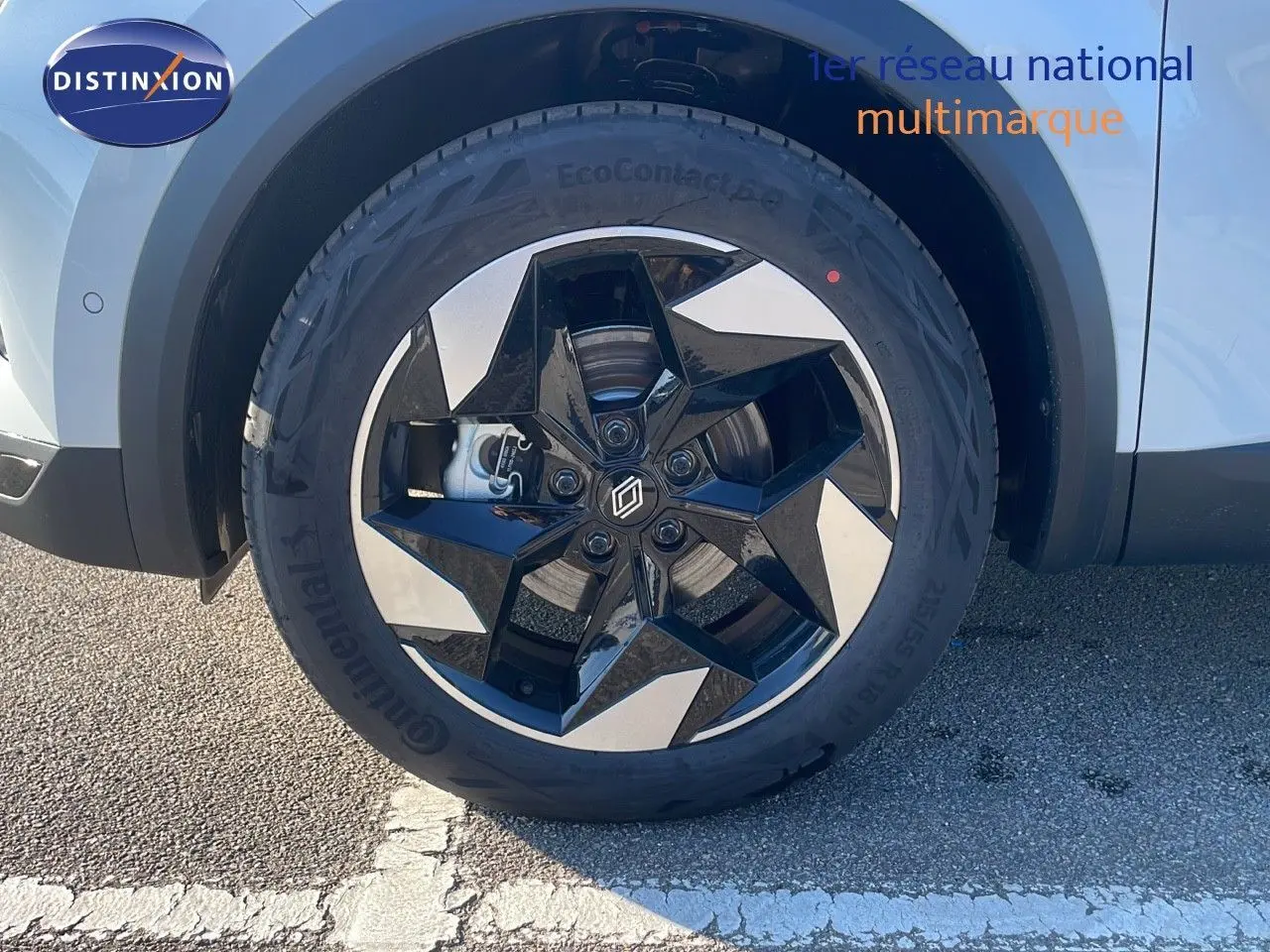 Gros plan sur la roue avant gauche du Renault Captur blanc nacré avec jante noire et argentée à design étoilé.