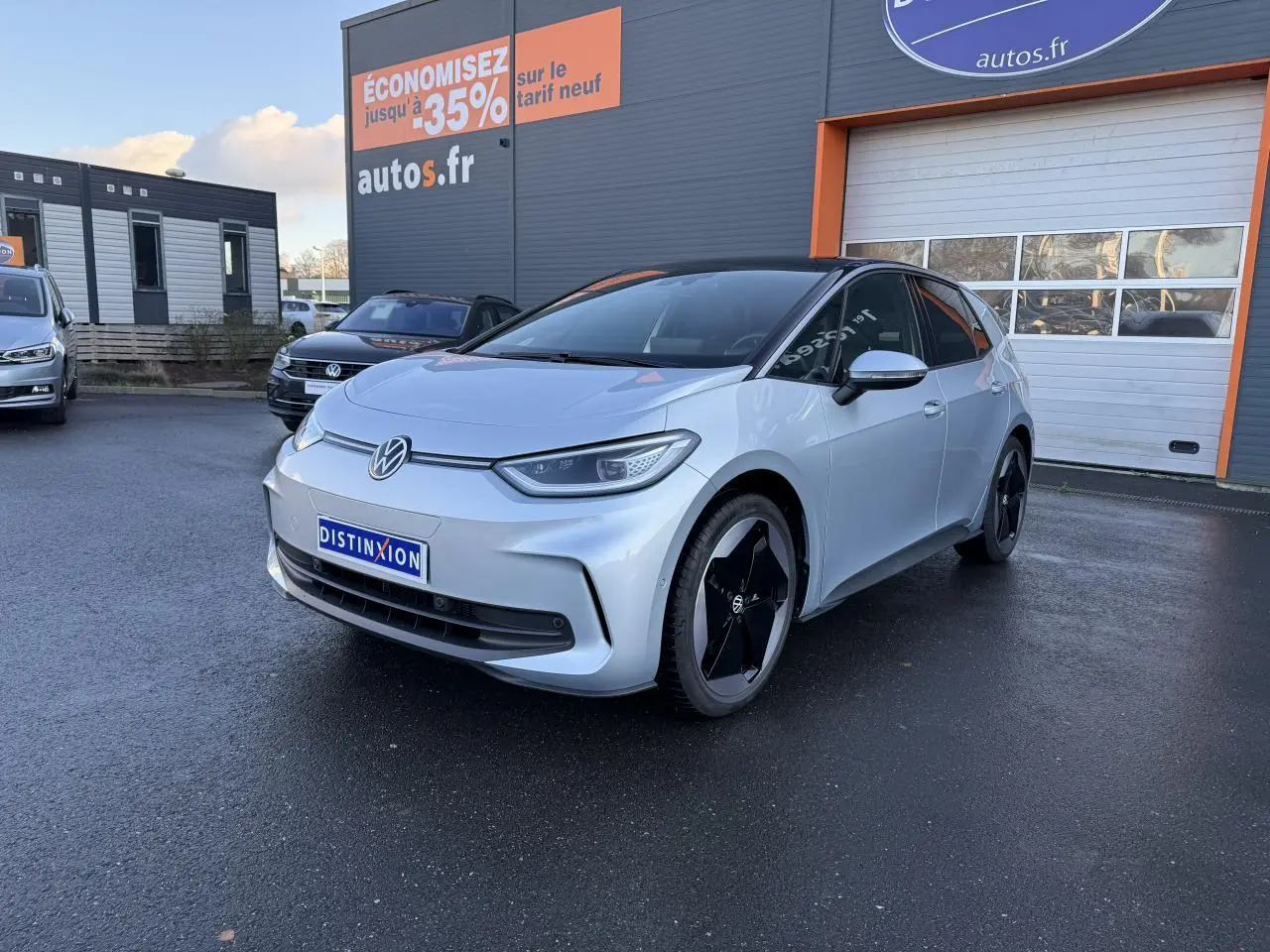 Vue 3/4 avant droite d'une Volkswagen ID.3 Pro S gris argent avec toit noir, stationnée devant un garage autos.fr
