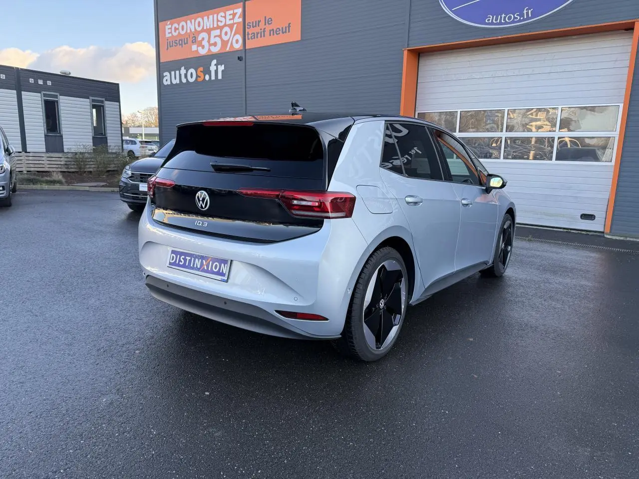 Vue 3/4 arrière droite d'une Volkswagen ID.3 Pro S gris argent avec toit noir et jantes noires au parking d'un concessionnaire.