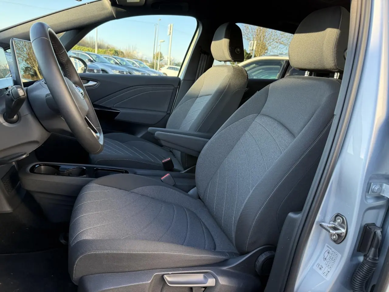 Vue intérieure côté conducteur du Volkswagen ID.3 Pro S 2025 gris argent, sièges tissu gris et volant multifonction.