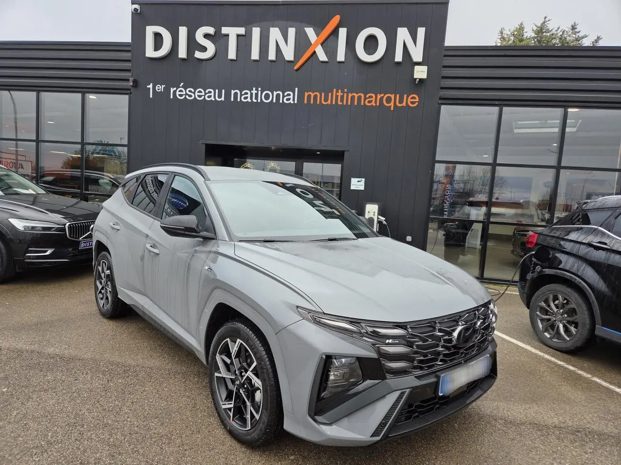 Hyundai Tucson 2025 gris métallisé en 3/4 avant droit, avec calandre N Line noire et jantes alliage 19 pouces.
